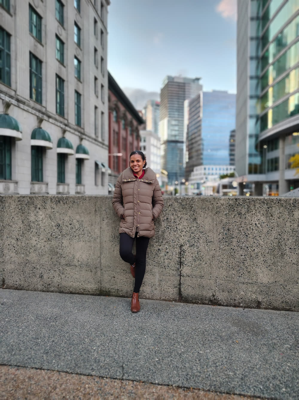 Zaida Rosario sonriendo, apoyada en un muro de concreto en el centro de una ciudad.